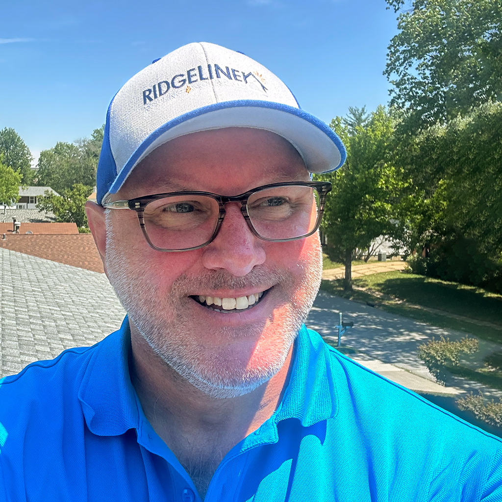 Chip Brewer, Project Manager with Ridgeline Roofing and Solar of Joplin, MO, is smiling with the backdrop of a roof replacement.