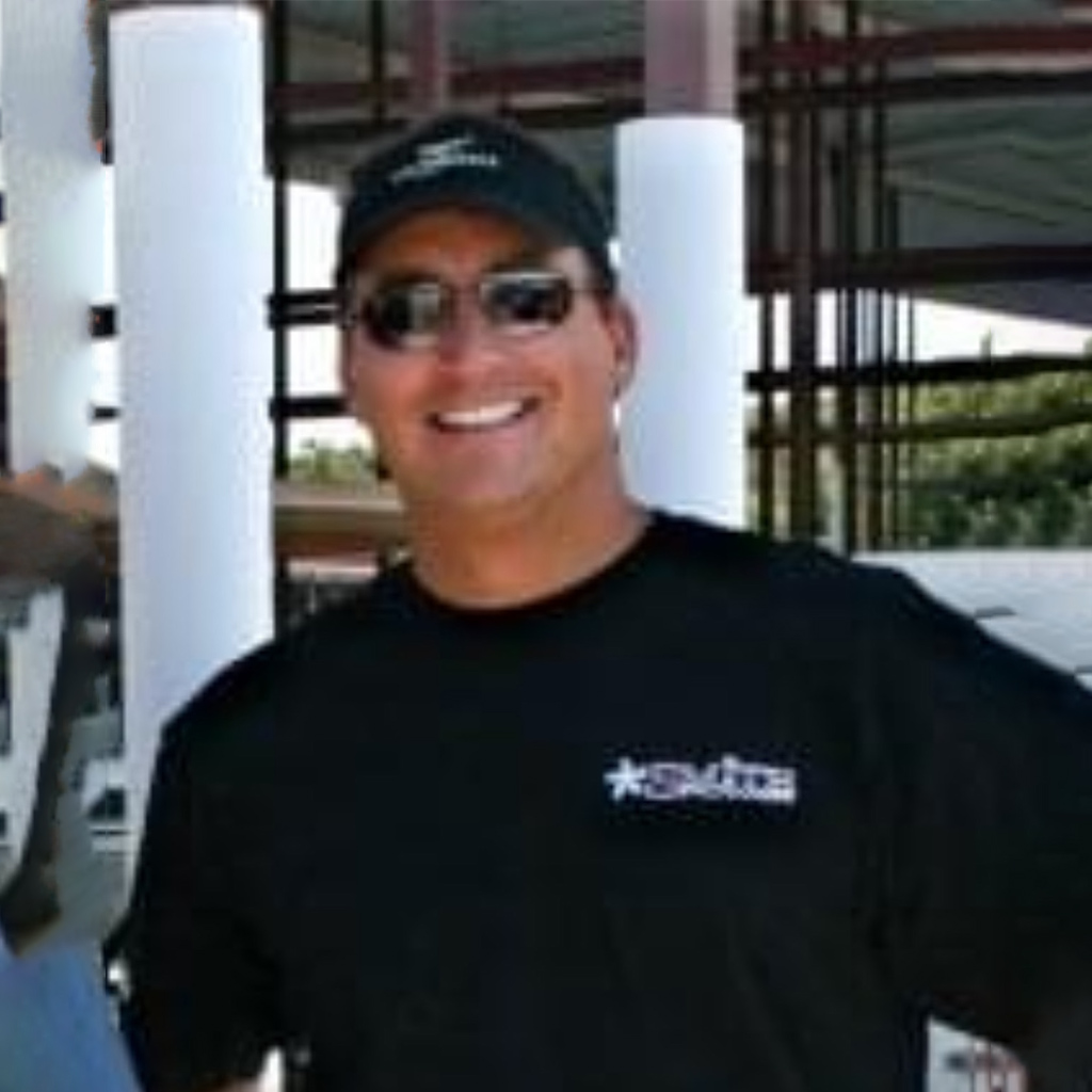 This is a photo of Jim Barbuto, Project Manager of Ridgeline Roofing and Solar in Oklahoma. He is standing amongst some structure with sunglasses and a ball cap.