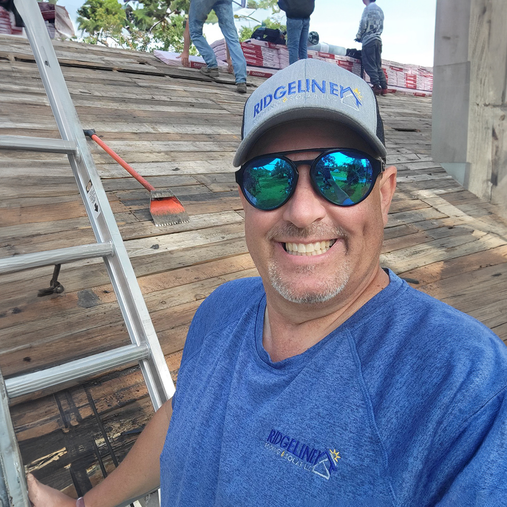 Matt Grooms is a Project Manager with Ridgeline Roofing and Solar in Joplin, MO standing on a ladder next to a roof under construction.