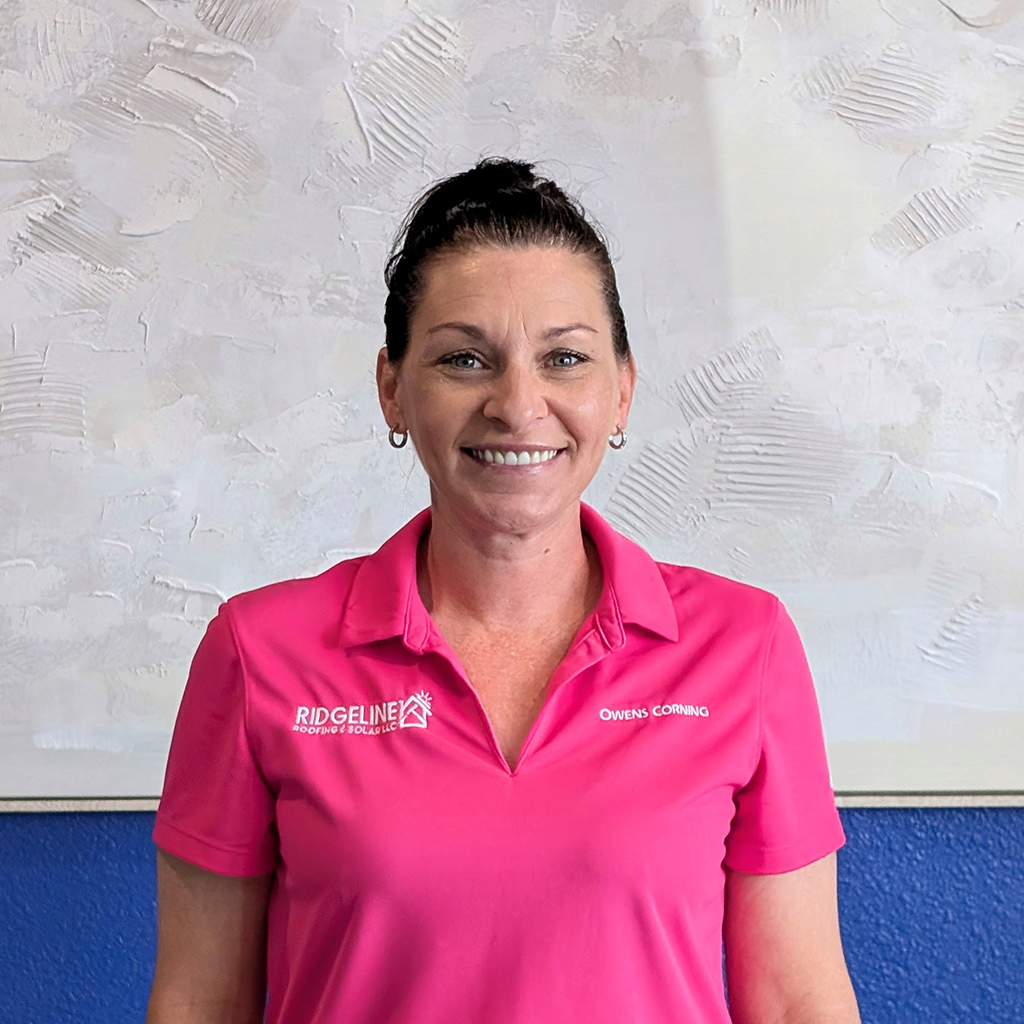 Michelle Donaldson, Office Manager of Ridgeline Roofing and Solar in Joplin, MO standing in front of a white painting.